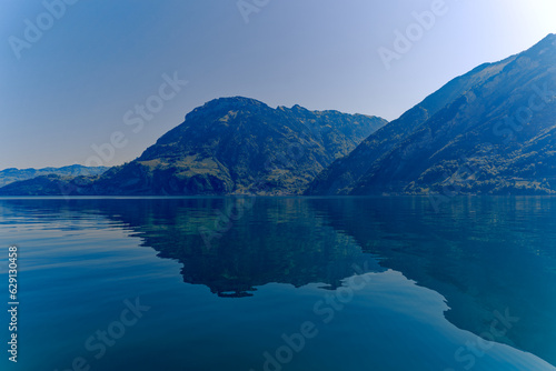 Scenic view of Lake Lucerne with Swiss Alps and mountain panorama seen from lakeshore of village Fl  elen on a sunny spring day. Photo taken May 22nd  2023  Fl  elen  Switzerland.