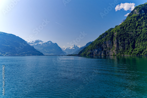 Scenic mountain panorama with Lake Lucerne in the foreground and Swiss village Flüelen in the background on a sunny spring day. Photo taken May 22nd, 2023, Lake Lucerne, Switzerland. © Michael Derrer Fuchs