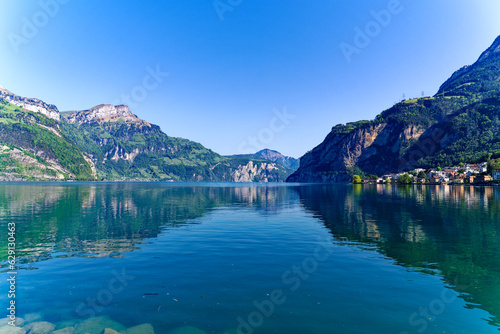 Scenic view of Lake Lucerne with Swiss Alps and mountain panorama seen from lakeshore of village Fl  elen on a sunny spring day. Photo taken May 22nd  2023  Fl  elen  Switzerland.