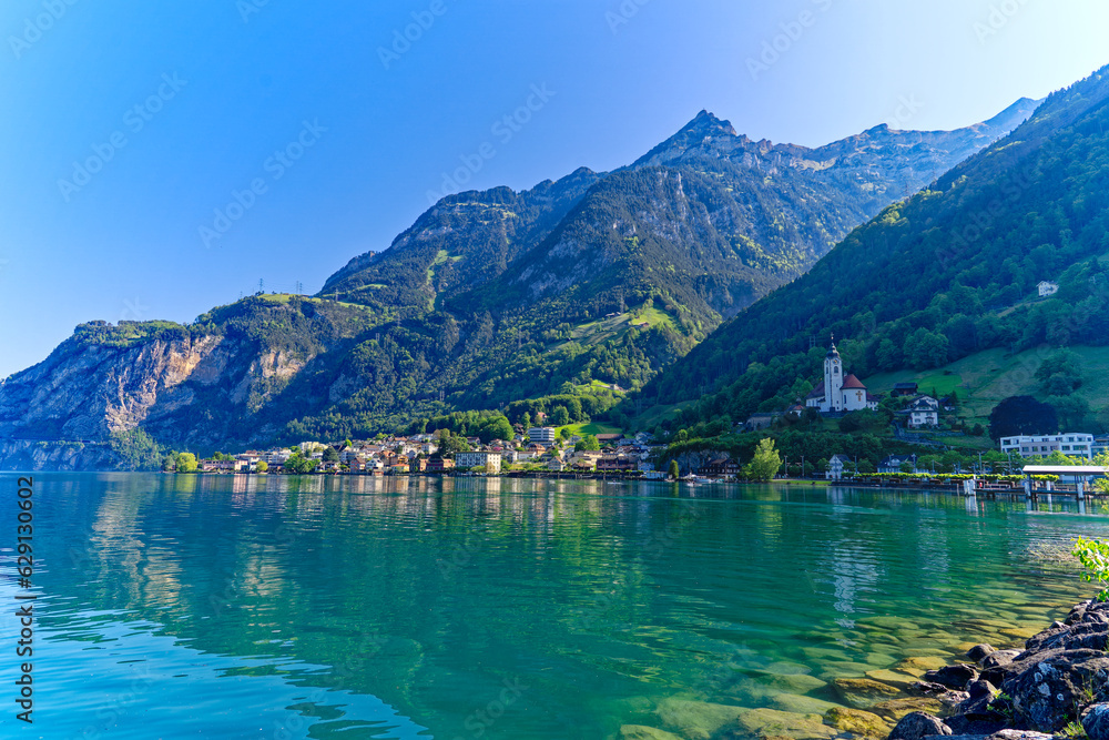 Scenic view of Swiss village of Flüelen with beautiful reflections in water on a sunny spring morning. Photo taken May 22nd, 2023, Flüelen, Canton Uri, Switzerland.