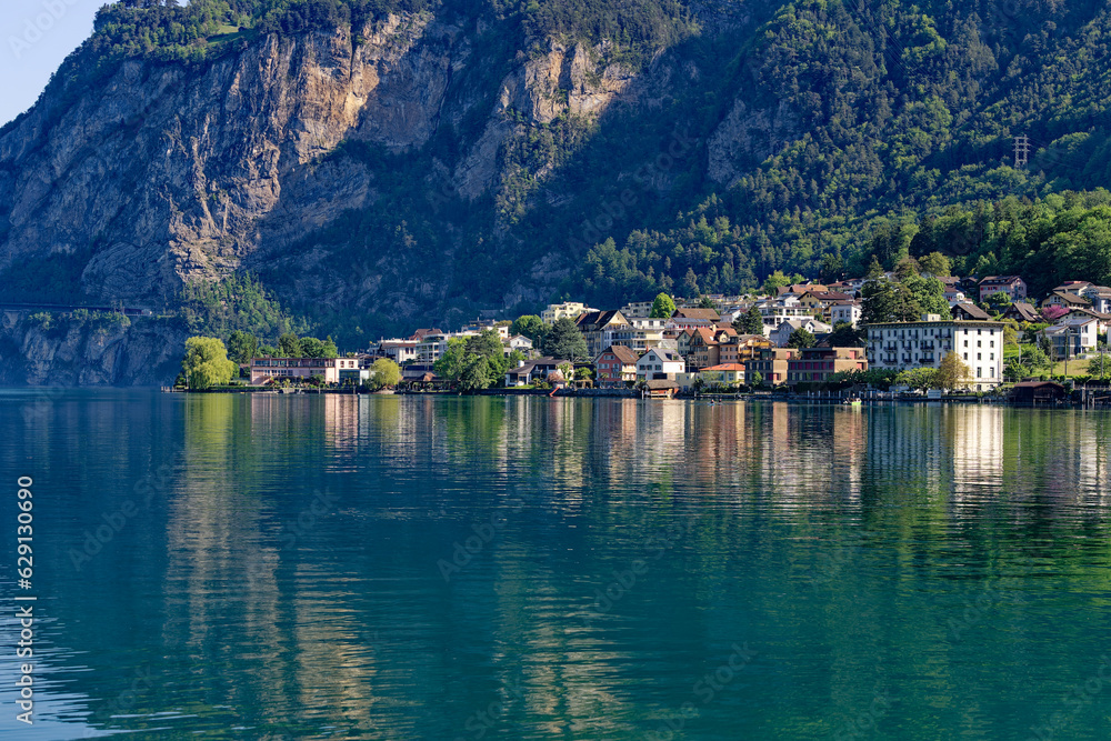 Scenic view of Swiss village of Flüelen with beautiful reflections in water on a sunny spring morning. Photo taken May 22nd, 2023, Flüelen, Canton Uri, Switzerland. Scenic view of Swiss village of Flüelen with beautiful reflections in water on a sunny spring morning. Photo taken May 22nd, 2023, Flüelen, Canton Uri, Switzerland.