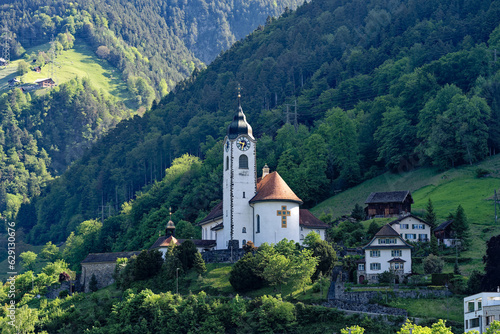 Mountain panorama at Swiss village of Flüelen on a sunny spring morning with church tower on a sunny spring morning. Photo taken May 22nd, 2023, Flüelen, Canton Uri, Switzerland.