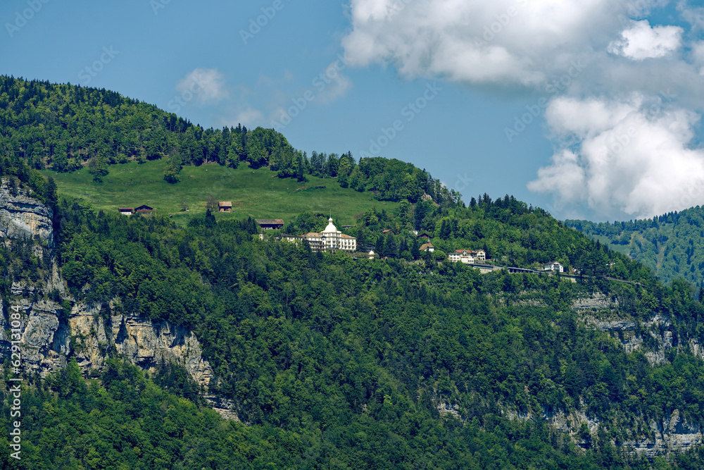 Scenic view of mountain panorama at Lake Lucerne with Swiss village of Seelisberg on top of mountain on a sunny spring day. Photo taken May 22nd, 2023, Sisikon. Switzerland.