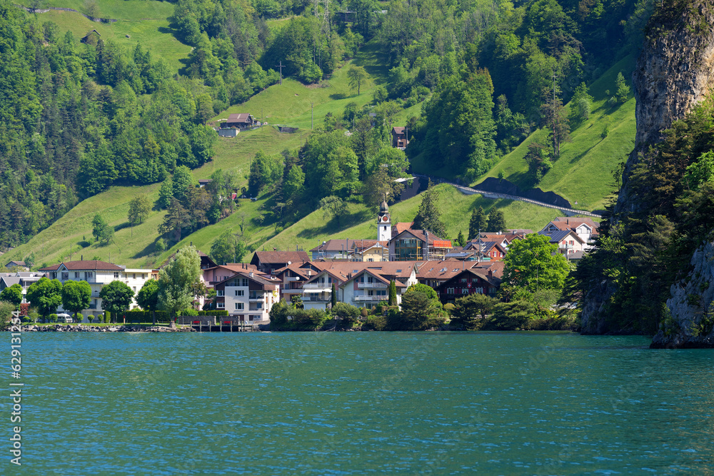 Scenic view of Lake Lucerne with Swiss village Sisikon mountain panorama seen from lakeshore on a sunny spring day. Photo taken May 22nd, 2023, Lake Uri, Switzerland.