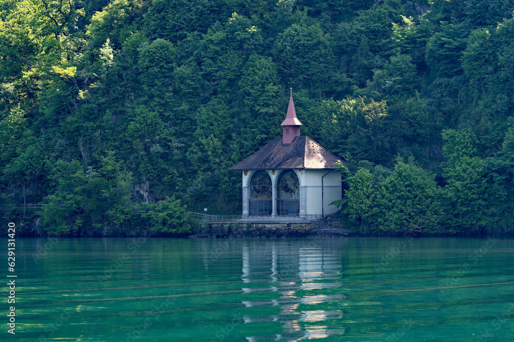 Famous Tell's Chapel at lakeshore of Lake Uri on a sunny spring day with woodland in the background. Photo taken May 22nd, 2023, Sisikon, Canton Uri, Switzerland.