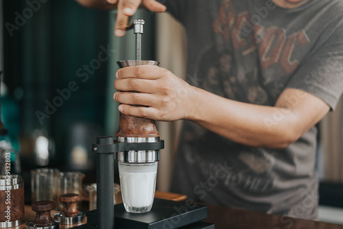 Professional barista making fresh coffee from ARAM espresso machine. Close up of hands barista brewing dirty coffee by handmade coffee machine in counter coffee shop.