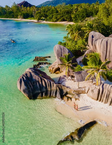 Anse Source d'Argent, La Digue Seychelles, a young couple of men and women on a tropical beach during sunset, drone aerial view