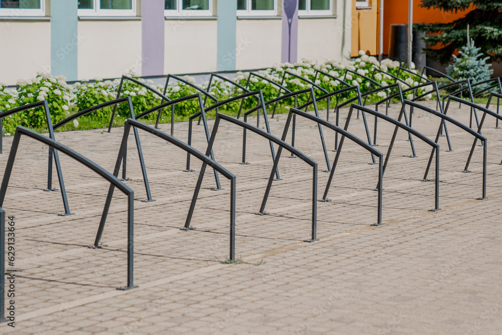Fototapeta premium Black metal bike parking metal frames next to a school. Creative stylish design for bicycles