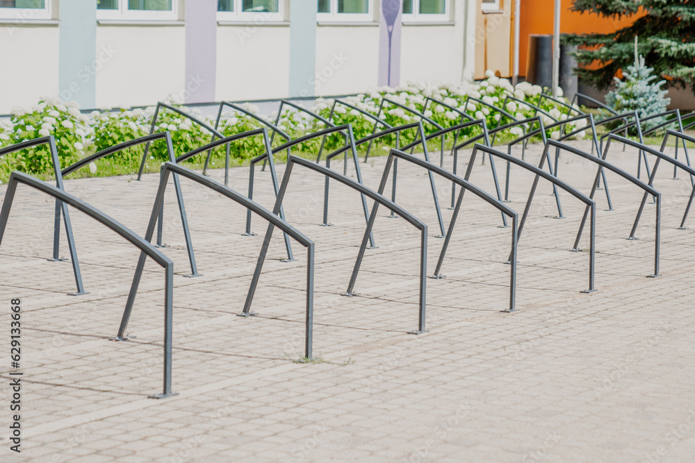 Black metal bike parking metal frames next to a school. Creative stylish design for bicycles Black metal bike parking metal frames next to a school. Creative stylish design for bicycles
