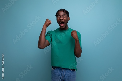 joyful ethnic african young man with dreadlocks in a casual t-shirt against the background with copy space