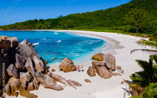 Anse Cocos La Digue Seychelles, a young couple of men and women on a tropical beach during a luxury vacation in Seychelles. Tropical beach Anse Cocos La Digue Seychelles with a blue ocean
