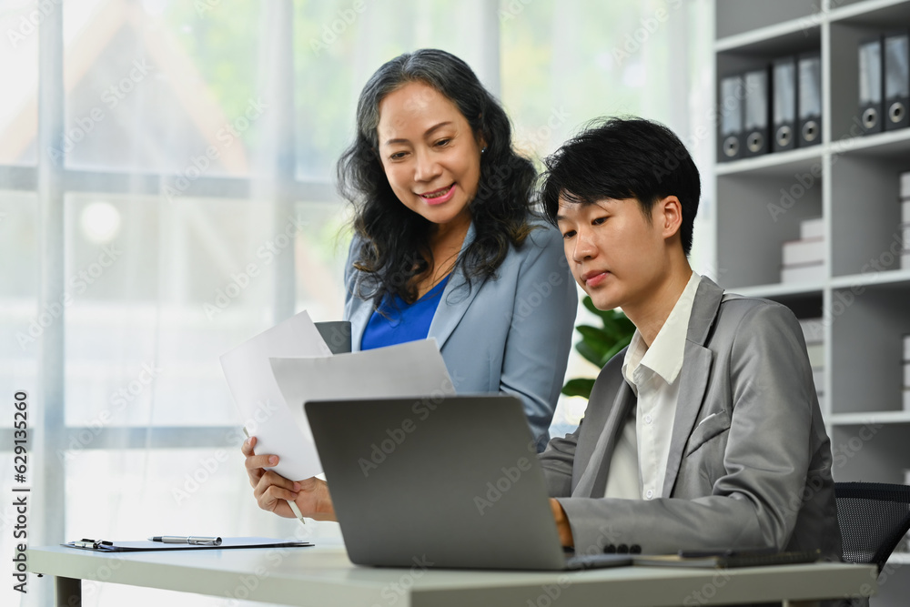 Senior female manager explaining information, discussing business plan with young businessman Senior female manager explaining information, discussing business plan with young businessman