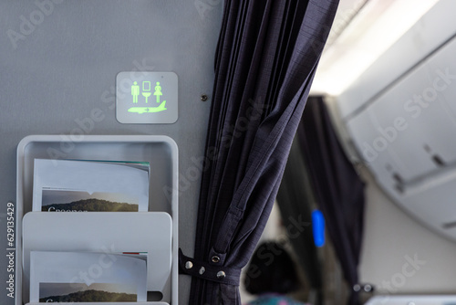 Fotografie Lavatory signage on airplan cabin wall lighted green suggests it is not occupied
