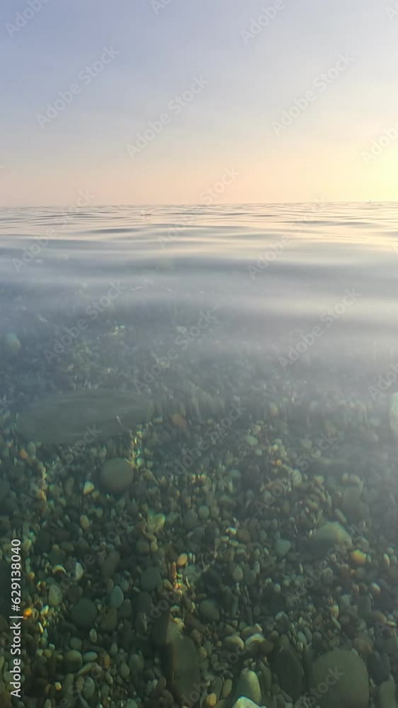Vertical aerial view on sea water surface, camera flies over clear sea water. Sun glare. Abstract nautical summer ocean nature. Holiday, vacation and travel concept. Nobody. Vertical video Vertical aerial view on sea water surface, camera flies over clear sea water. Sun glare. Abstract nautical summer ocean nature. Holiday, vacation and travel concept. Nobody. Vertical video