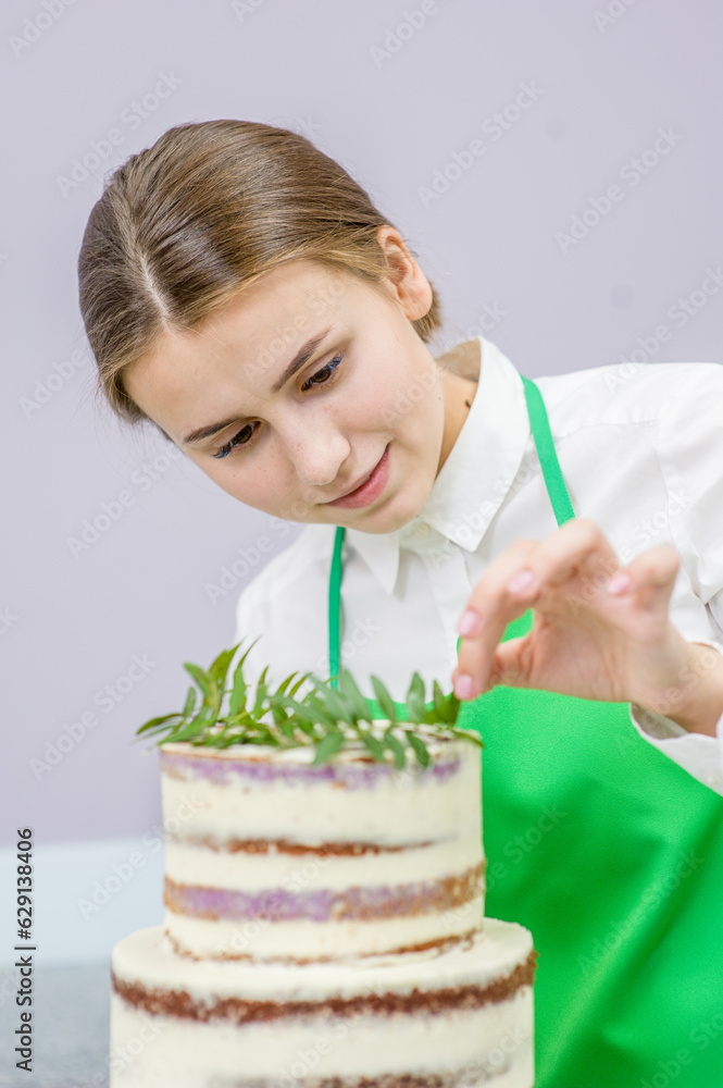 Young woman decorating delicious cake with pistachio leaves