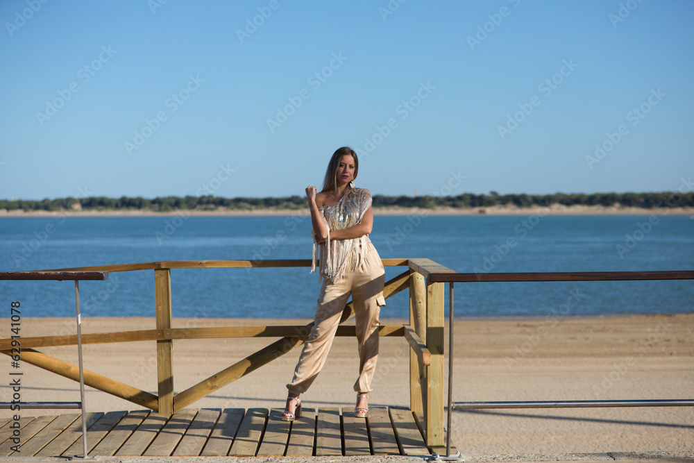 Beautiful young blonde woman walks along the promenade on the south coast of spain in Sanlucar de barrameda, city of wine and gastronomy, in the background the mouth of the river guadalquivir. Beautiful young blonde woman walks along the promenade on the south coast of spain in Sanlucar de barrameda, city of wine and gastronomy, in the background the mouth of the river guadalquivir.