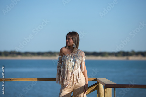 Beautiful young blonde woman walks along the promenade on the south coast of spain in Sanlucar de barrameda, city of wine and gastronomy, in the background the mouth of the river guadalquivir. photo