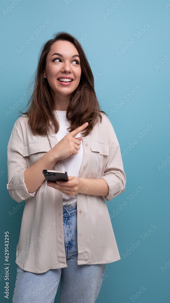 Charming brunette 30 year old female person dressed in a shirt and jeans shows her hand at an advertising offer Charming brunette 30 year old female person dressed in a shirt and jeans shows her hand at an advertising offer