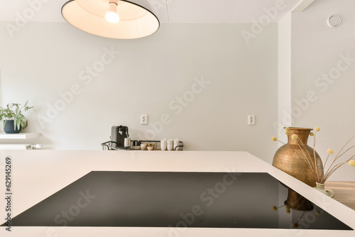 a kitchen with white counter tops and black counterstop in the center of the room is a pot of yellow flowers