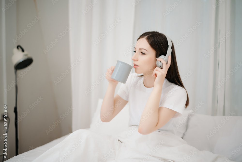 Beautiful woman has woken up on a white bed and holding coffee in the morning at home in morning Beautiful woman has woken up on a white bed and holding coffee in the morning at home in morning