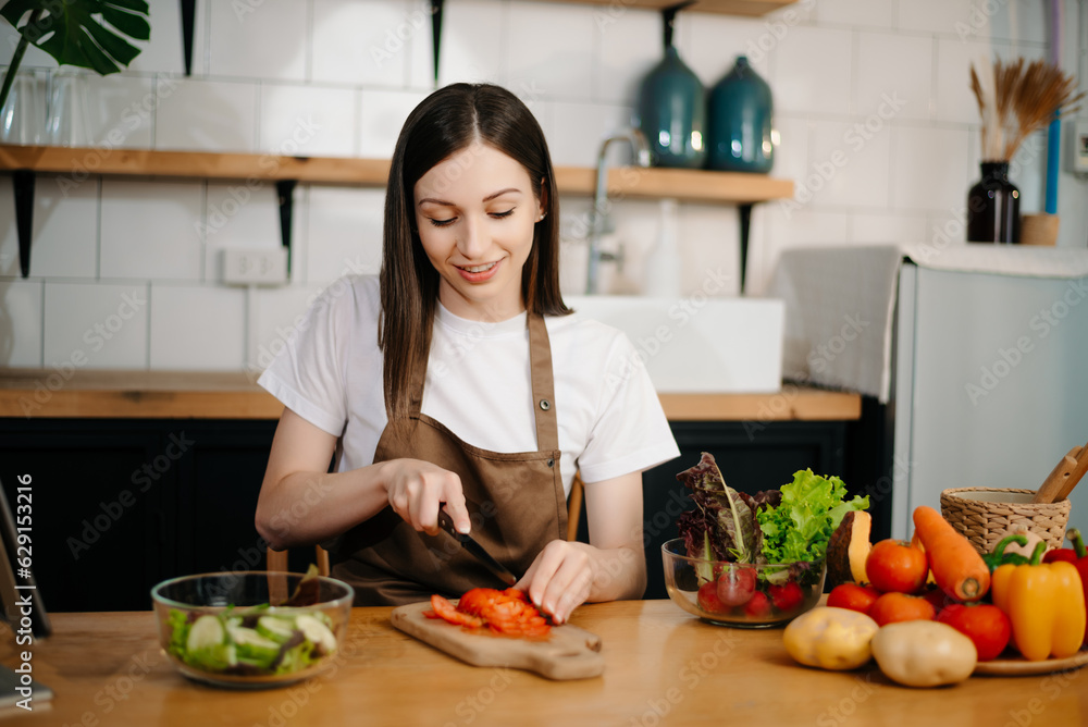 young woman with cutting board of cut lettuce at kitchen. healthy food concept.