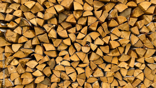 Wall of firewood, background of dry chopped firewood. Preparation of firewood for baths and stoves. Wooden background. Background texture of chopped wood
