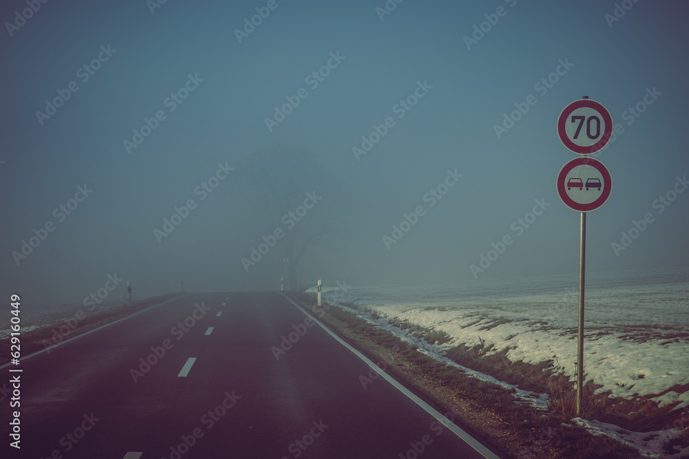 Winter landscape with a road leading into the fog. Speed limit, no ...