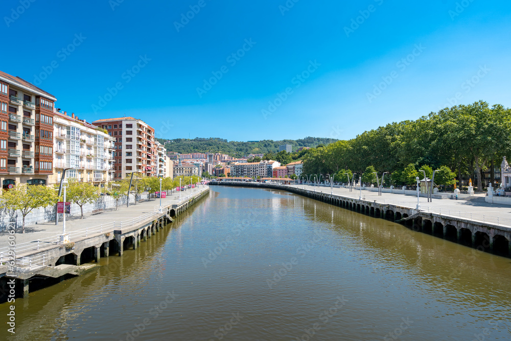 Bilbao, SPAIN - July 19 2022: Bilbao city center. View of Nervion River with promenade area. At the right Arenal Park. Bilbao is the largest city in the Basque Country, beautiful travel destination