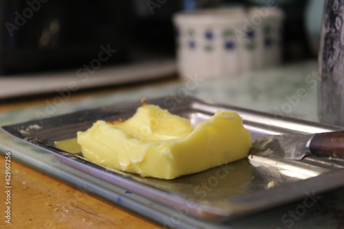 Slika na platnu A close up photo of a slab of butter on a metal plate on a wooden counter