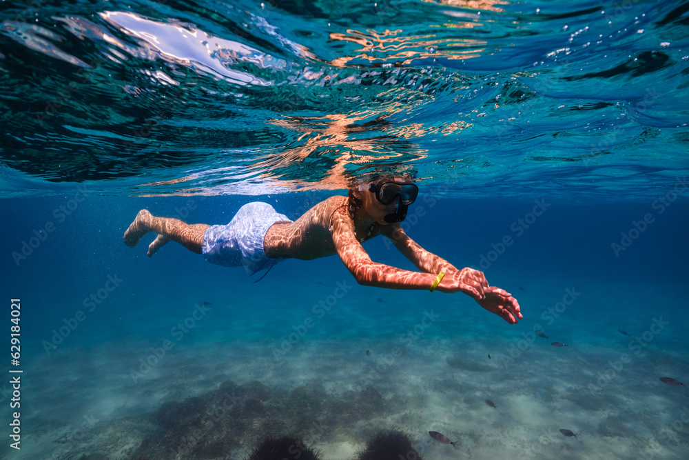 Boy snorkeling in blue seawater