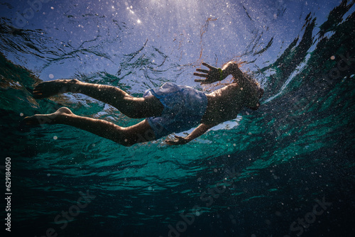 Preteen kid in diving mask snorkeling in seawater