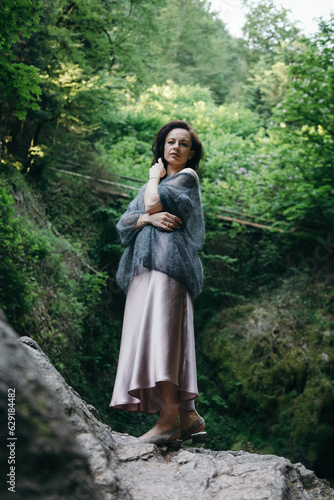 Beautiful young woman sitting on rock near mountain river in forest. High quality photo