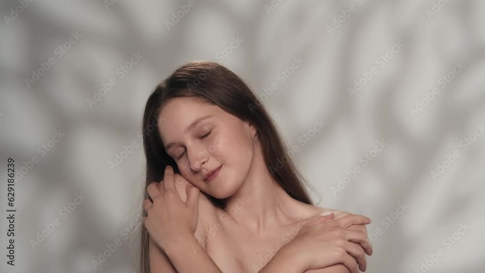 Appealing female model touching her shoulders pure skin, looking at the camera smiling. Appealing female model touching her shoulders pure skin, looking at the camera smiling.