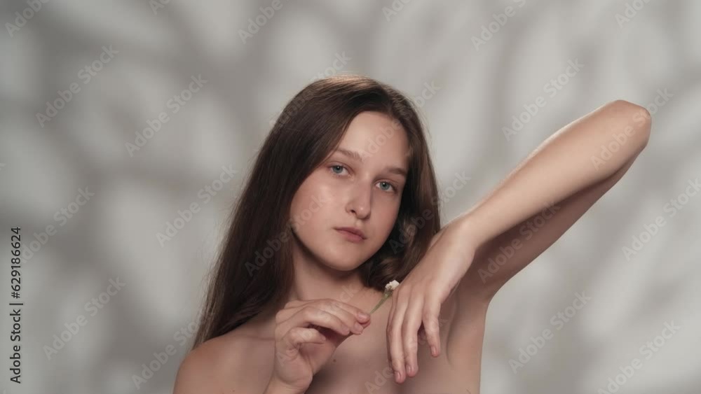 Attractive young girl with blue eyes playing with flower, looking at the camera Attractive young girl with blue eyes playing with flower, looking at the camera