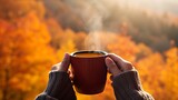 A person's hands holding a mug of steaming hot beverage