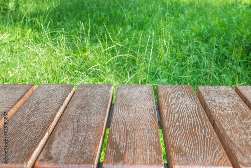 Wooden table with green grass on the background.