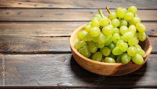 Bunch of green ripe grapes in a wooden bowl, on rustic wood background
