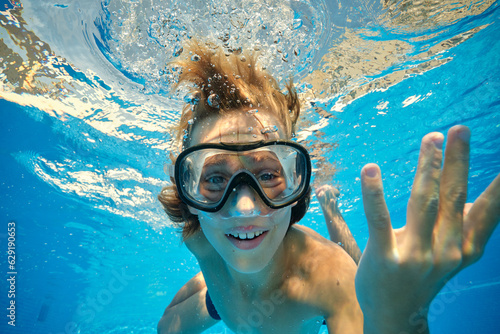 Positive boy swimming in goggles in pool