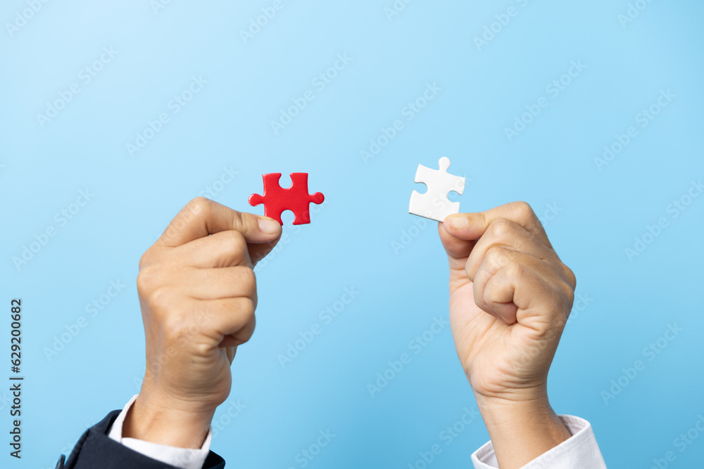 Two hands trying to connect couple puzzle piece on blue background. Teamwork concept. Closeup hand of connecting jigsaw puzzle. Two hands trying to connect couple puzzle piece on blue background. Teamwork concept. Closeup hand of connecting jigsaw puzzle.