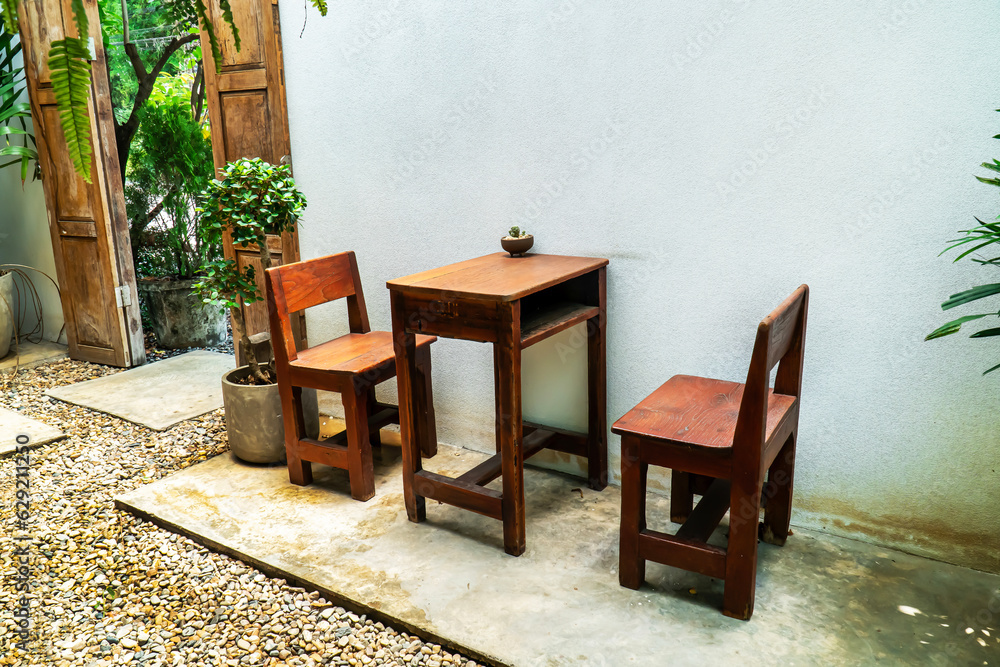 Wood table and chairs in the garden. Vintage square wood table and two chair in ornamental garden.