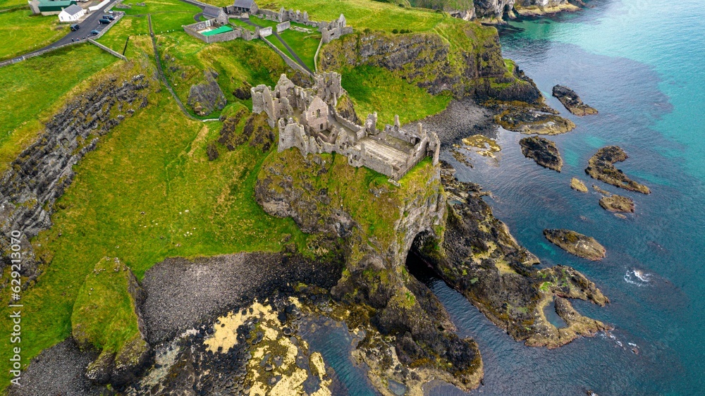 Picturesque landscape featuring the Dunluce Castle on a hill overlooking the shimmering blue water