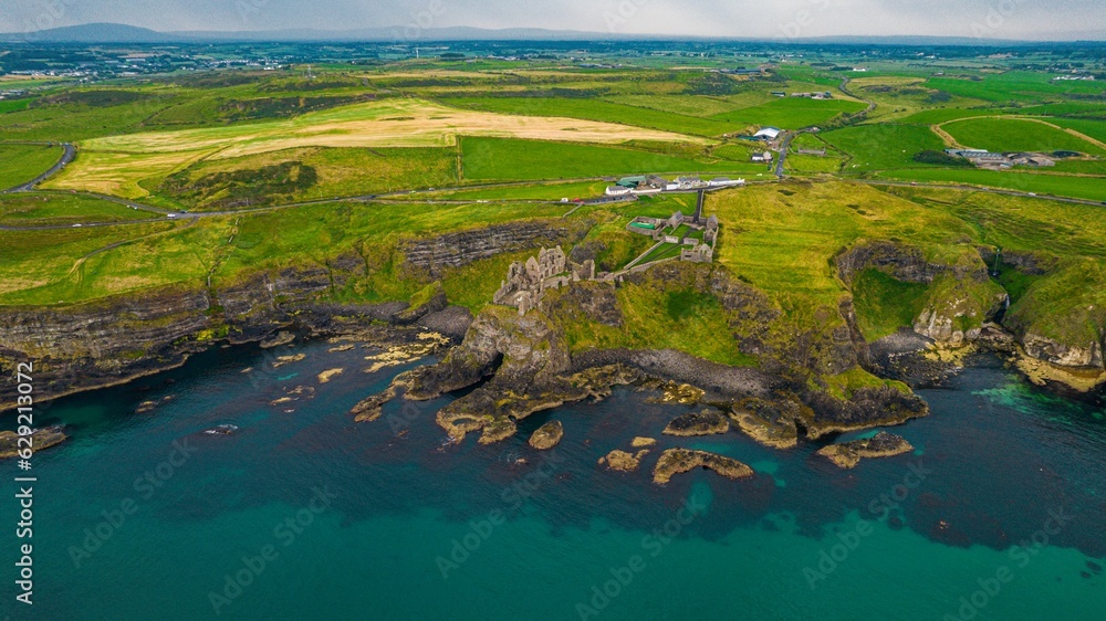 Aerial view of a scenic, green island in Ireland, featuring the Dunluce Castle
