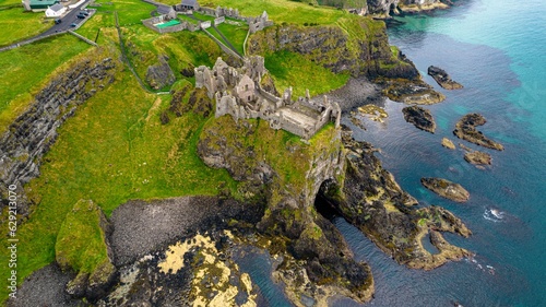 Picturesque landscape featuring the Dunluce Castle on a hill overlooking the shimmering blue water photo