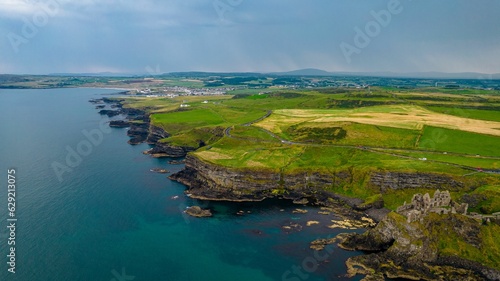 Aerial view of the historic Dunluce Castle and the green fields surrounding it