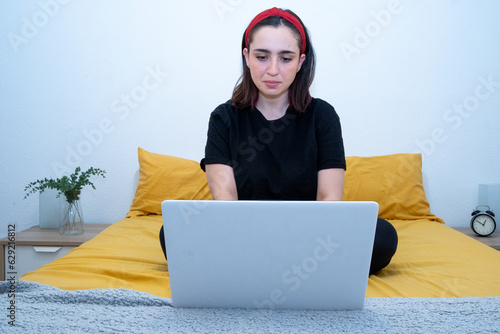 Balance entre trabajo y comodidad: Instantánea de una mujer exitosa realizando sus tareas laborales desde la cama