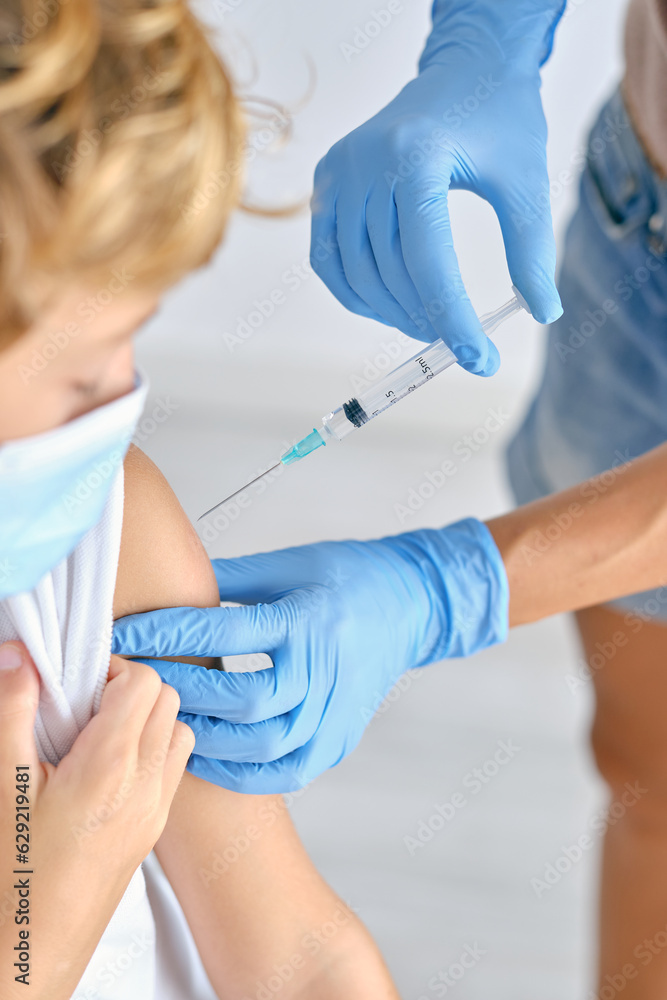 Crop nurse with syringe vaccinating patient in hospital Crop nurse with syringe vaccinating patient in hospital