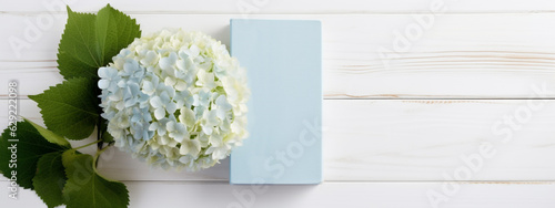 Blue-white hydrangea with a clear blue book, diary on a white wooden background. Mockup for your own design