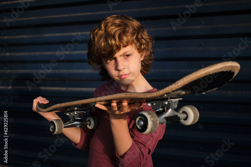 Boy examining skateboard against blue wall