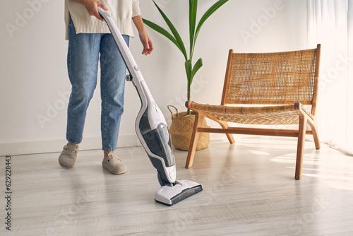 Crop unrecognizable female cleaning home with contemporary cordless vacuum cleaner photo