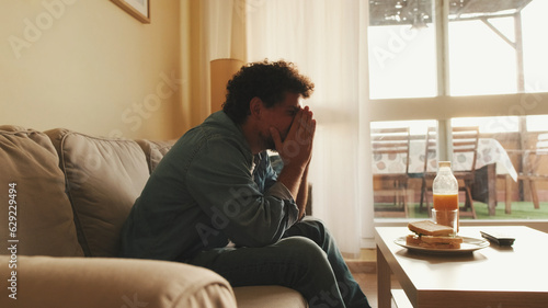 Guy dressed in denim shirt has lunch, sits in the living room and emotionally watches sports game on TV